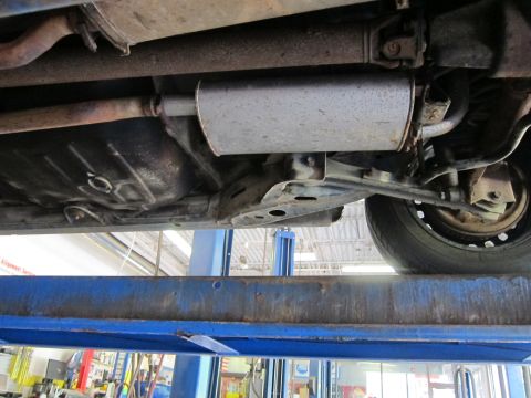 1991 Ford LTD Crown Victoria - The underside of a vehicle is viewed from below while it is raised on a hydraulic lift.