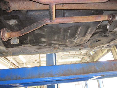 1991 Ford LTD Crown Victoria - Underside view of a vehicle's exhaust system and fuel tank, showing some rust.