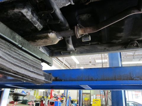 1991 Ford LTD Crown Victoria - Underside view of a vehicle's exhaust system, including the catalytic converter, on a lift.