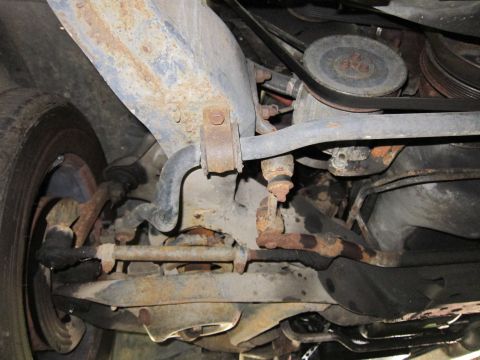 1991 Ford LTD Crown Victoria - A close-up view of the vehicle's undercarriage reveals rusty suspension parts and a drive belt pulley system.