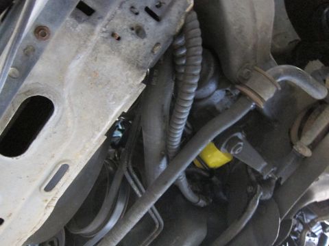 1991 Ford LTD Crown Victoria - Underside view of car suspension components and hoses, with a yellow oil filter visible.