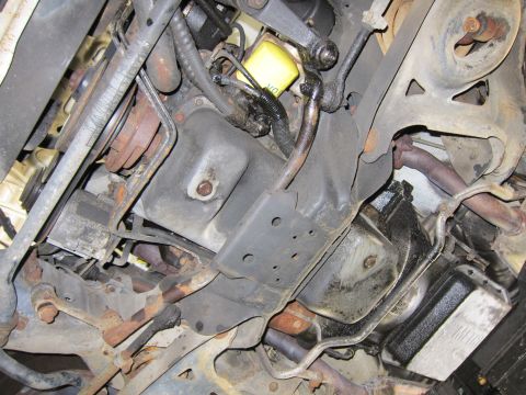 1991 Ford LTD Crown Victoria - The underside of the vehicle shows the engine oil pan, exhaust pipes, and various suspension parts, with visible signs of rust and wear.