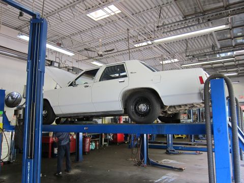 1991 Ford LTD Crown Victoria - A white 1991 Ford Crown Victoria LTD is raised on a hydraulic lift in a service bay.