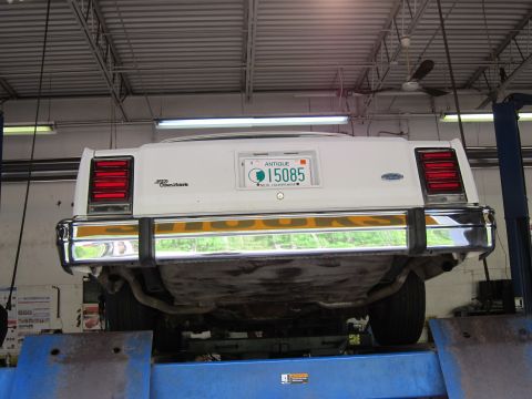 1991 Ford LTD Crown Victoria - Rear view of a white 1987 Ford Crown Victoria on a lift, displaying an antique New Hampshire license plate.