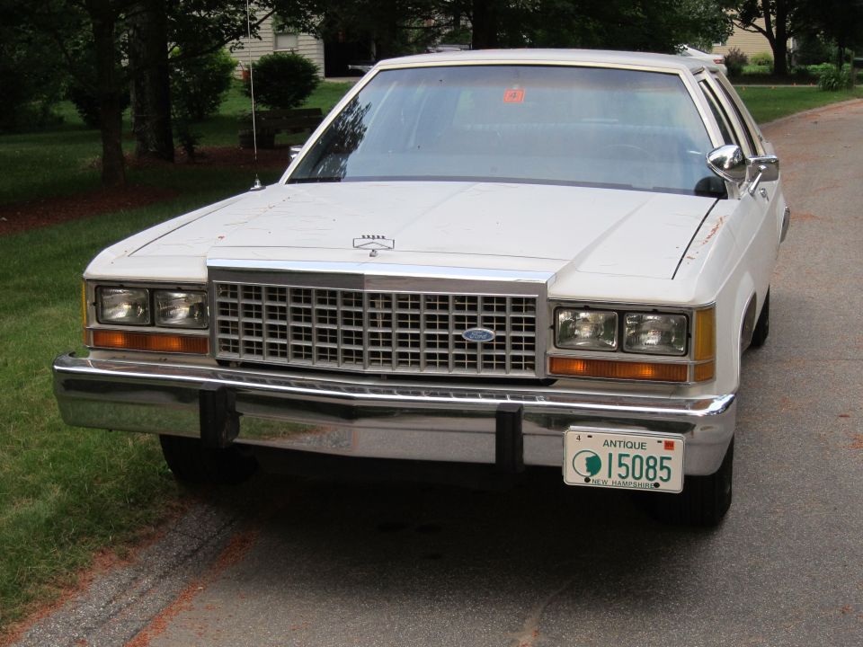 1991 Ford Crown Victoria LTD front view. White sedan with chrome grille and antique license plate