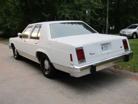 1991 Ford LTD Crown Victoria - This white sedan is seen from the rear, with a license plate displaying '15085'.