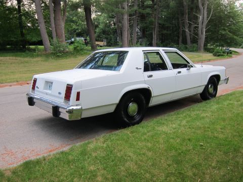 1991 Ford LTD Crown Victoria - This 1991 Ford Crown Victoria LTD is seen from its rear three-quarter angle, parked on a roadside with a grassy embankment.