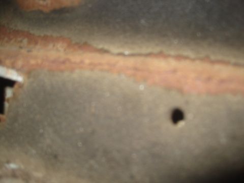 1993 Ford Bronco - This image shows a close-up of a rusted metal panel with a hole, likely a vehicle part.