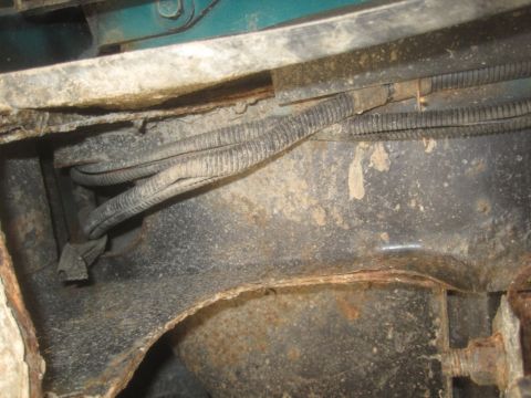 1993 Ford Bronco - Close-up of a corroded vehicle frame showing wiring harness and rust damage.