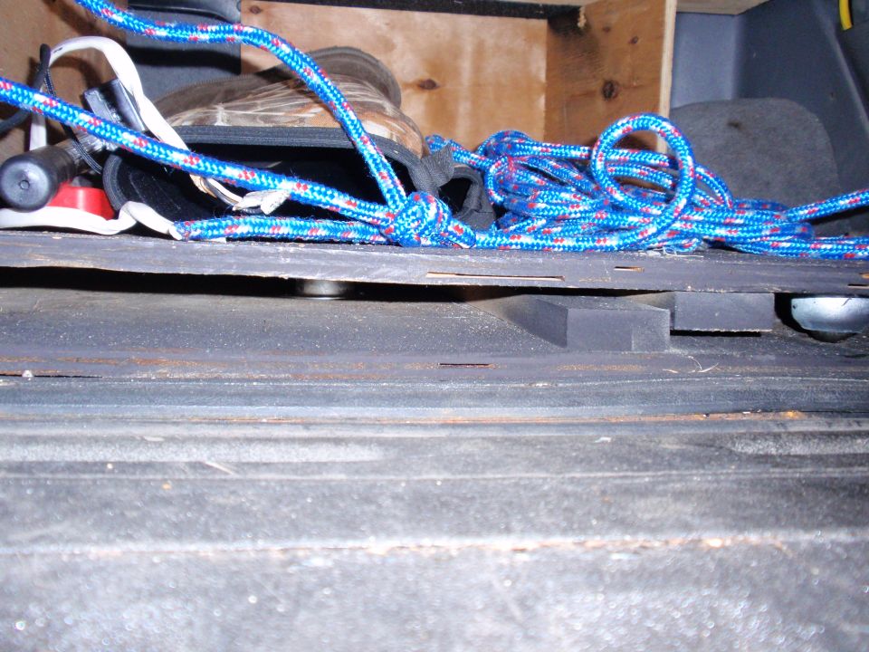 Rope coiled on a flat surface inside a vehicle, with boots and other items in the background