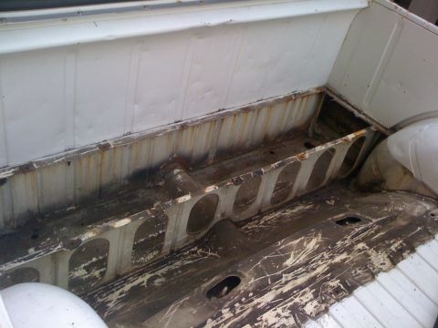 1964 Ford Ranchero - The interior of a truck bed shows significant rust and damage to the metal structure.