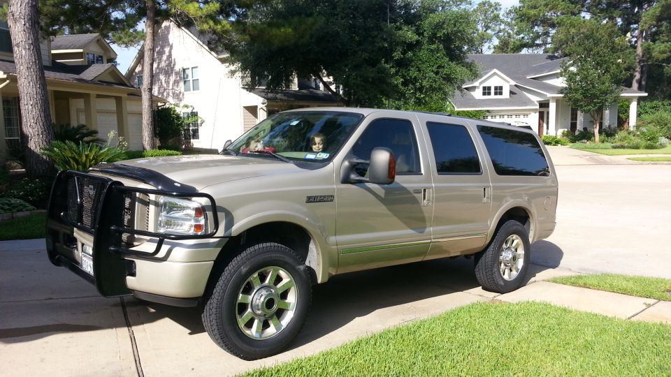 Gold 2005 Ford Excursion parked in a suburban driveway with a brush guard
