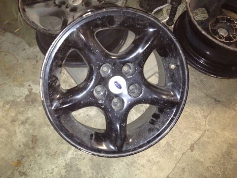 2000 Ford E350 - A single black Ford wheel is shown, with other wheels stacked behind it.