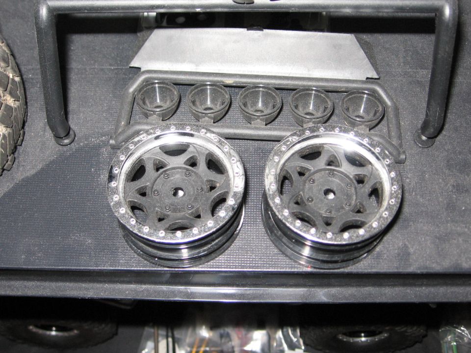 Two black and chrome toy truck wheels stacked, with a tire on the left