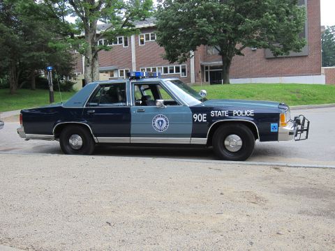 1991 Ford LTD Crown Victoria - vintage Massachusetts State Police cruiser, a navy-and-gray Ford LTD Crown Victoria marked '90E STATE POLICE', parked outside a brick build…