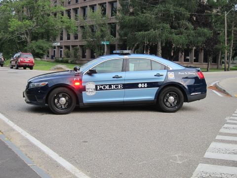 1991 Ford LTD Crown Victoria - two-tone blue Ford Police Interceptor sedan lettered 'POLICE 911' with red light bar active, stopped at a crosswalk.