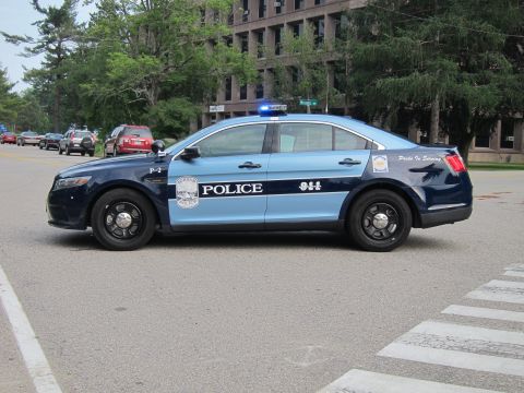 1991 Ford LTD Crown Victoria - two-tone blue Ford Police Interceptor sedan marked 'POLICE 911' and 'Pride In Serving', emergency lights on, near a crosswalk.
