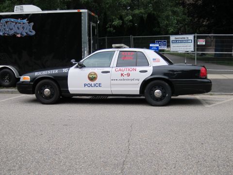 1991 Ford LTD Crown Victoria - Passenger side of a black-and-white Rochester Police Ford Crown Victoria K-9 unit with 'CAUTION K-9' and website lettering on the door.