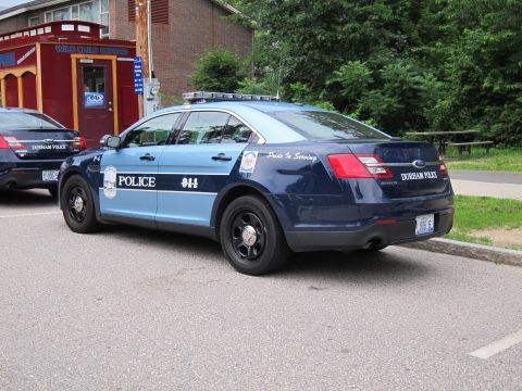 1991 Ford LTD Crown Victoria - two-tone blue Durham Police Ford Interceptor sedan with light bar, parked near a red kiosk with a second cruiser behind.