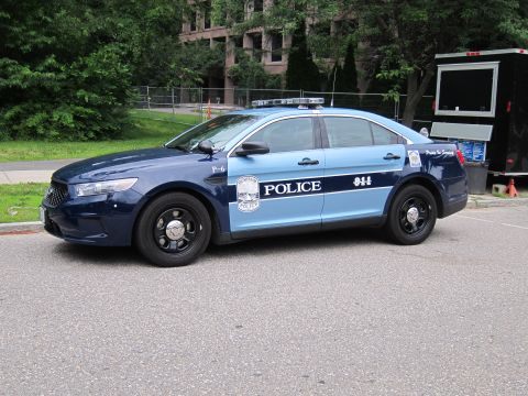 1991 Ford LTD Crown Victoria - Front quarter view of a two-tone blue Ford Police Interceptor marked 'POLICE 911' with shield emblem, parked beside a building.