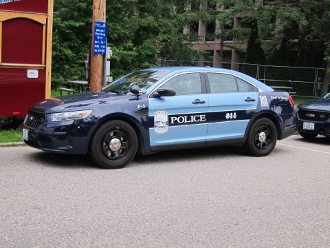 1991 Ford LTD Crown Victoria - Front quarter view of a two-tone blue Ford Police Interceptor sedan marked 'POLICE 911' parked near a red kiosk and trees.