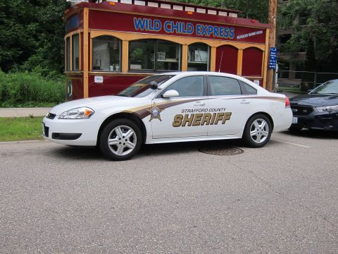 1991 Ford LTD Crown Victoria - Front quarter view of a white Strafford County Sheriff Chevrolet Impala with gold star emblem, parked by a red food kiosk.