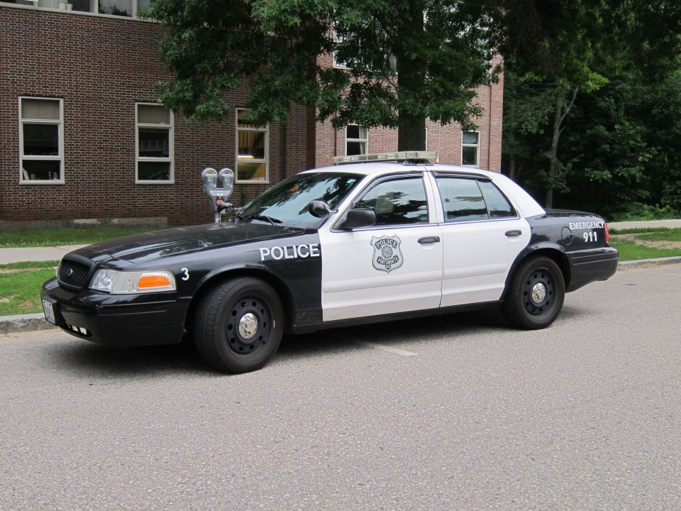 Black and white Ford Crown Victoria police car parked by a brick building
