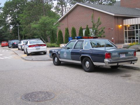 1991 Ford LTD Crown Victoria - two-tone blue Ford LTD Crown Victoria marked 'State Police' parked by a brick building, rear three-quarter view.