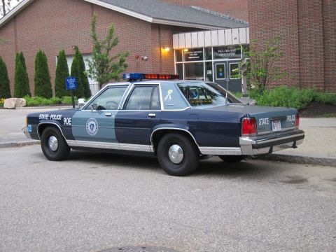 1991 Ford LTD Crown Victoria - two-tone blue Ford LTD Crown Victoria marked 'State Police 90E' parked outside a brick building.