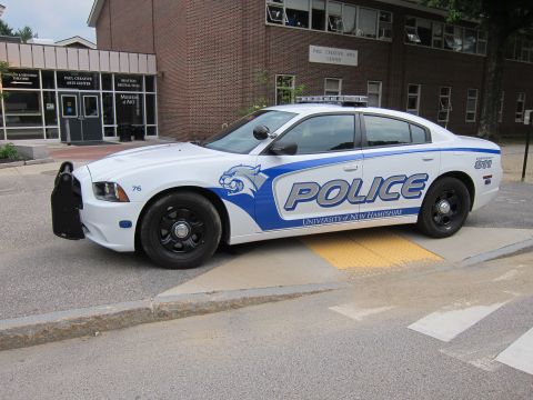 1991 Ford LTD Crown Victoria - white and blue Dodge Charger marked 'Police University of New Hampshire' with front push bar at a crosswalk.