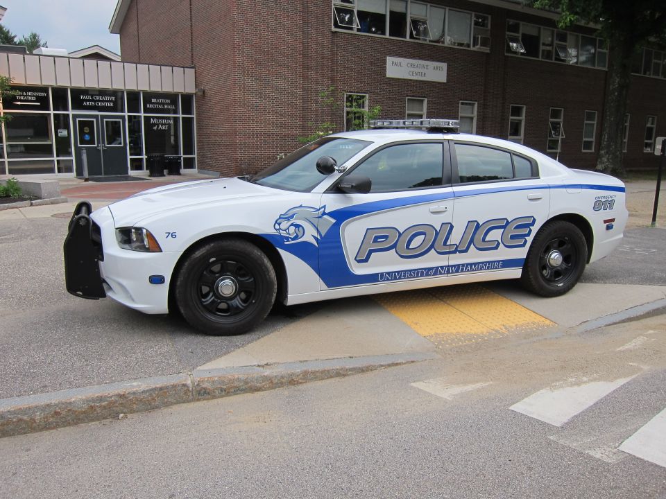 White and blue UNH Police Dodge Charger sedan with push bar, side view