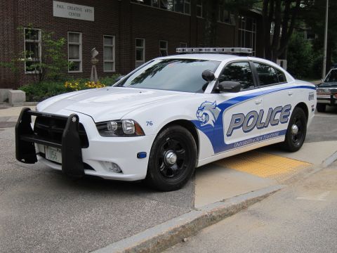 1991 Ford LTD Crown Victoria - Front three-quarter view of a white and blue Dodge Charger marked 'Police University of New Hampshire' with push bar.