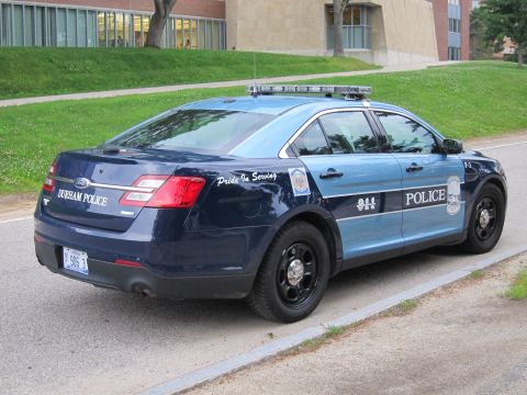1991 Ford LTD Crown Victoria - Rear three-quarter view of a two-tone blue Durham Police Ford sedan marked Police 9-1-1, parked along a curb.