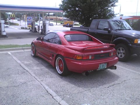 2003 Ford Crown Victoria - A red Toyota MR2 and a black pickup truck are parked at a gas station.