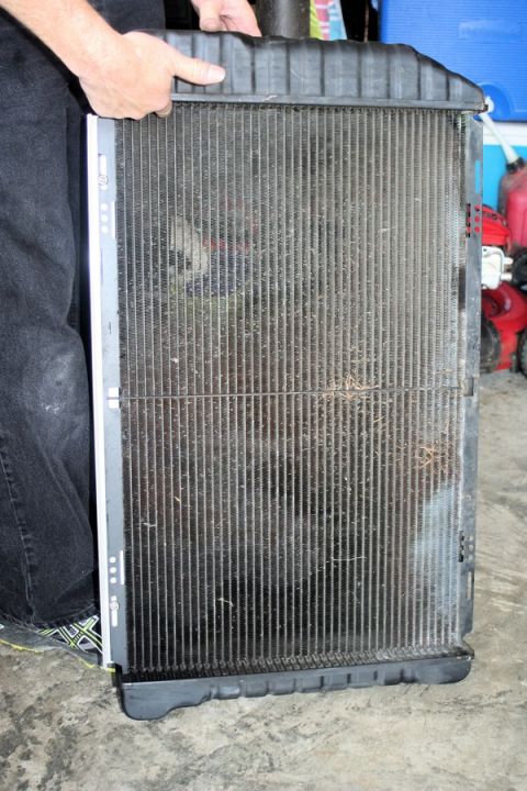 1976 Ford Ranchero - A person holds a vehicle radiator, showing its internal fins and construction.