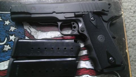 2000 Mercury Grand Marquis - A black Taurus pistol and two magazines are displayed on a surface with an American flag motif.