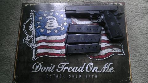 2000 Mercury Grand Marquis - A black semi-automatic pistol and three magazines are placed on a metal sign the Gadsden flag and the phrase 'Don't Tread On Me'.