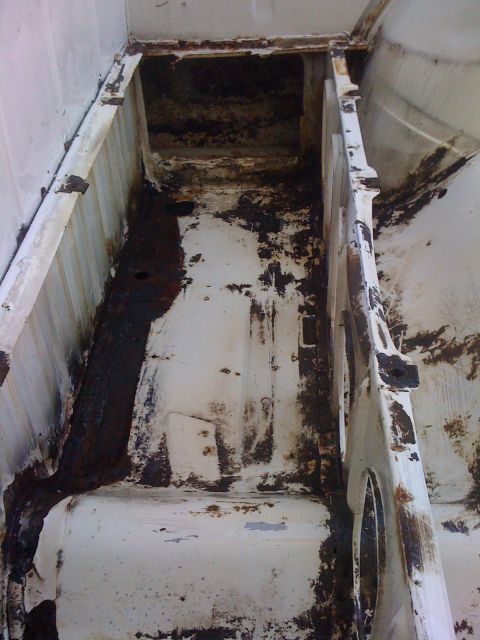1964 Ford Ranchero - The interior of a white truck bed shows significant rust and deterioration.