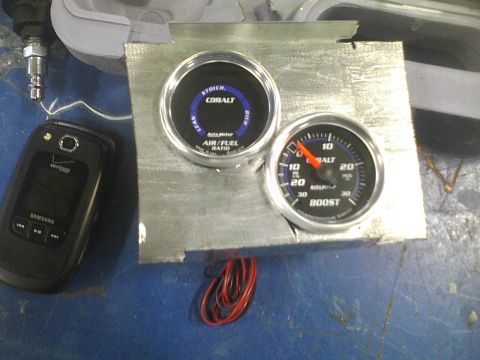 2003 Ford Crown Victoria - Two AutoMeter Cobalt gauges, one for air/fuel ratio and the other for boost, are mounted on a metal plate.