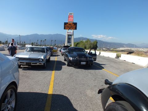 2003 Ford Crown Victoria - Cars line up in the staging lanes under an electronic Irwindale tower sign reading about hot rod and motorcycle events, mountains in the di…