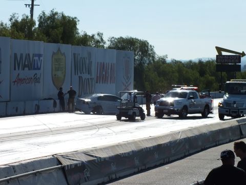2003 Ford Crown Victoria - wrecked silver car rests against the strip wall while a golf cart, safety pickup, and crew respond, an In-N-Out sign visible at right.