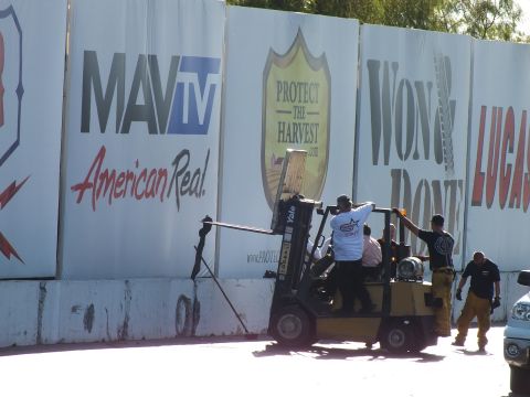 2003 Ford Crown Victoria - Track workers operate a yellow Yale forklift in front of MAVTV and Protect the Harvest banners at a drag strip.