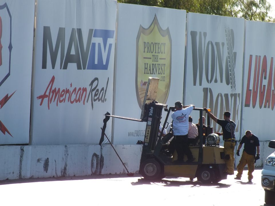 Track crew on a yellow Yale forklift in front of sponsor banners