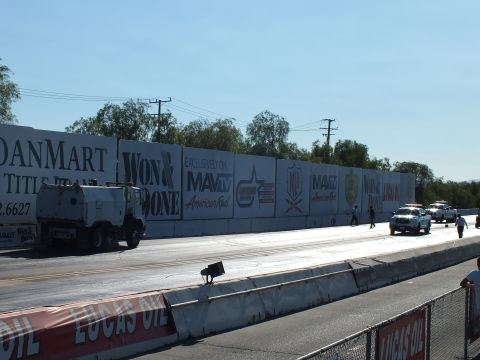 2003 Ford Crown Victoria - track-drying truck and white vehicles work the lanes of a drag strip lined with LoanMart and Lucas Oil banners.