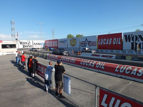 2003 Ford Crown Victoria - Spectators line the chain-link fence watching cars stage on the Irwindale Dragstrip beneath Lucas Oil and Won & Done banners.