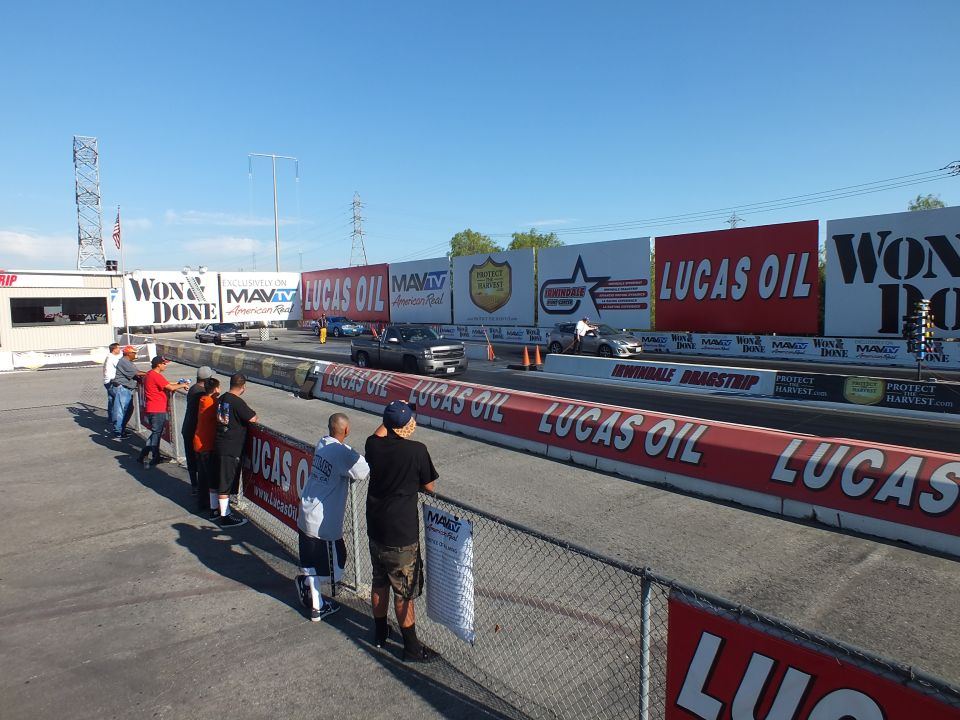 Spectators along the fence watching cars stage at Irwindale Dragstrip