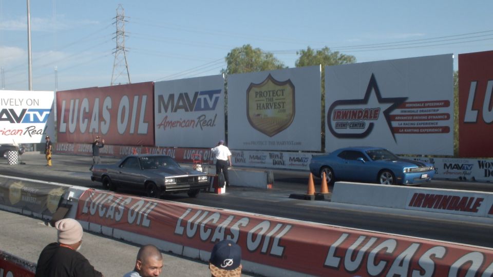 Dark sedan and blue Dodge Challenger staged on the drag strip