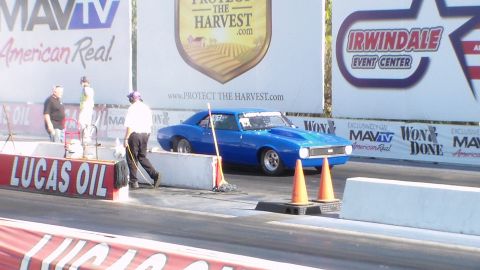 2003 Ford Crown Victoria - blue muscle car waits at the start line with crew and orange cones nearby, framed by MAVTV and Irwindale banners.