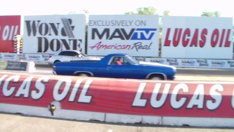 2003 Ford Crown Victoria - blue Chevrolet El Camino races a white car down the drag strip lanes beneath Won & Done and Lucas Oil banners.
