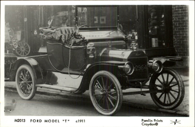 Ford Model T touring car with a soft top, parked outside a building